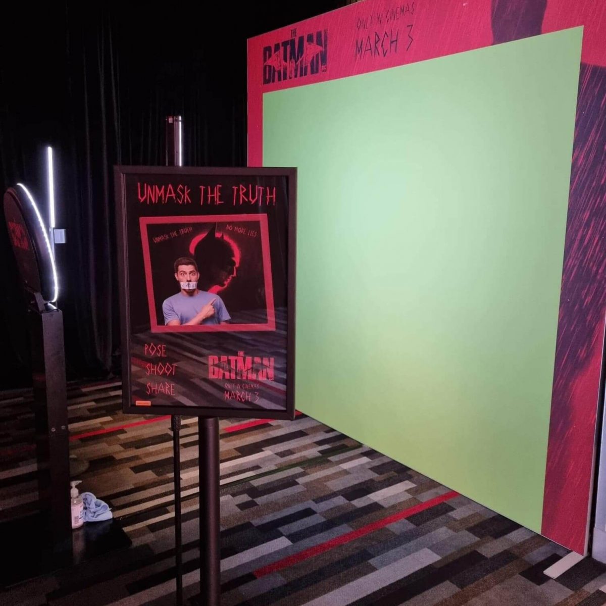 branded green screen set up at a movie premiere for batman with lights and signage and a photo booth