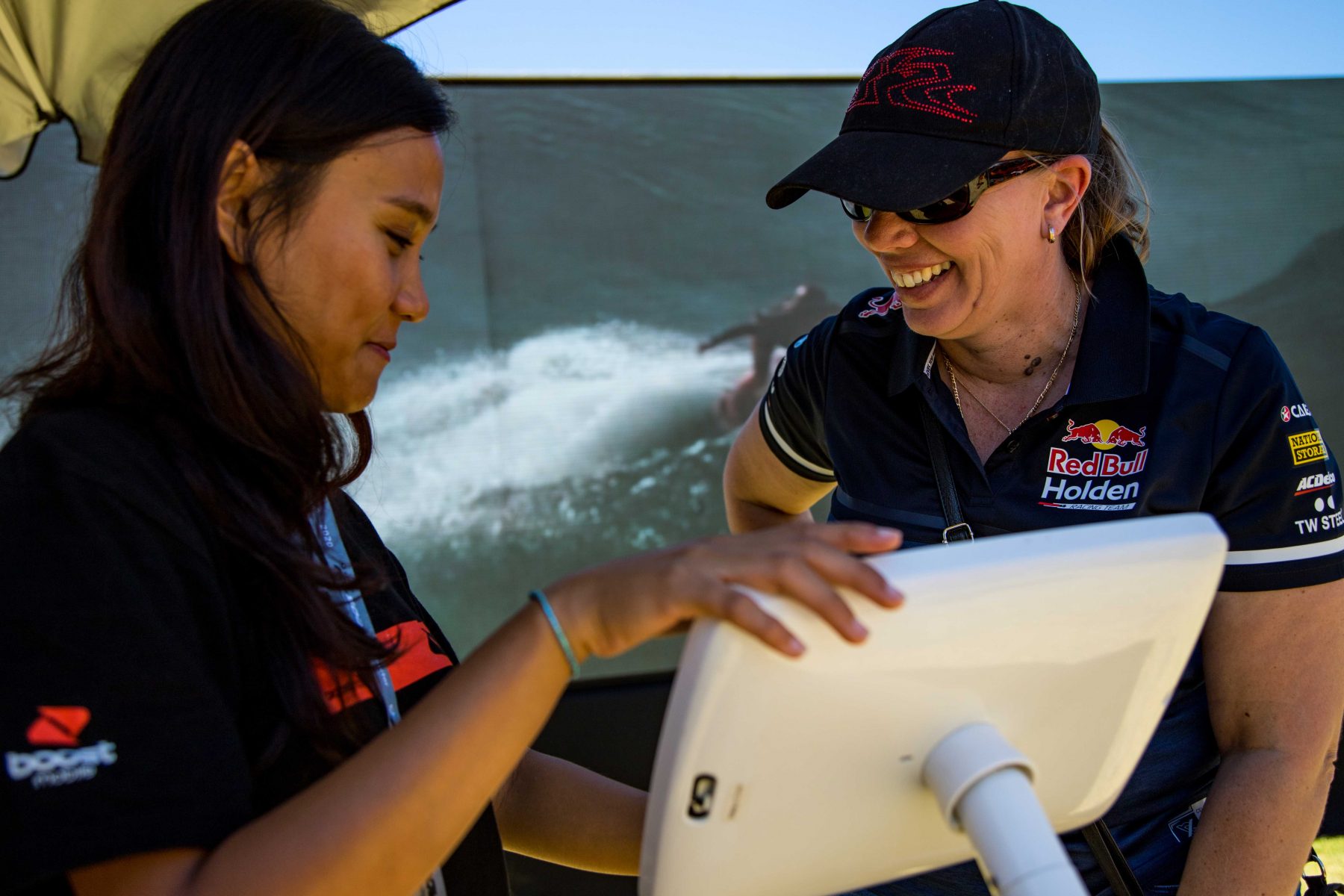 two woman smiling while using an ipad station