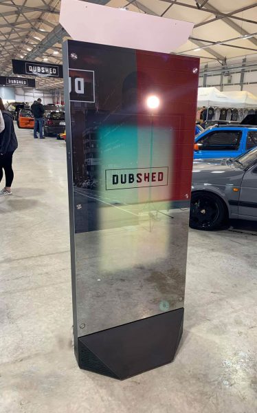 sleek mirror booth set up in the middle of an event with cars in the background and a screen that says dubshed